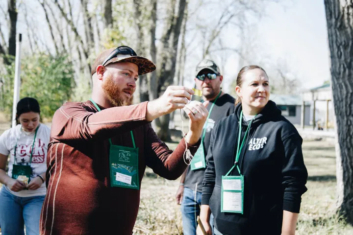 A bearded man teaches educators how to use forestry tools.