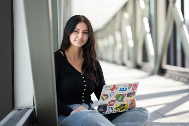 Courtney sitting in skyway on campus with her laptop