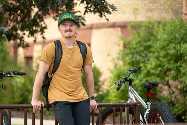 Dylan Purdy, a transfer student, leans against a campus bike rack