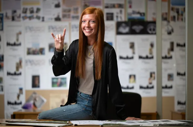 Student smiling confidently at camera with horns up!
