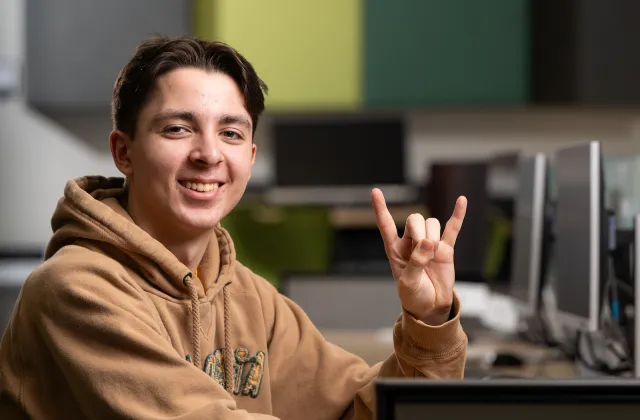 christopher in computer lab holding up horns symbol