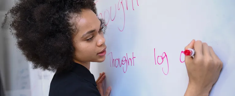 Female educator writing on a white board teaching a class