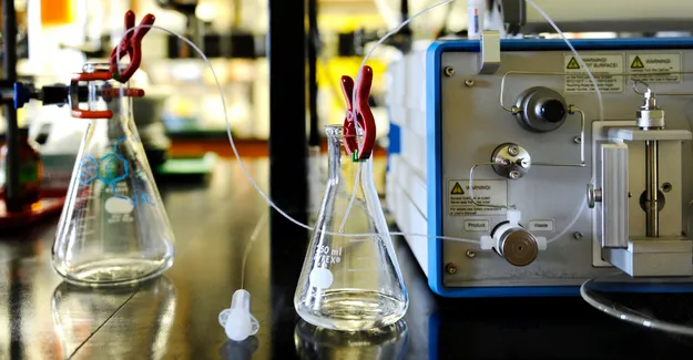 2 chemistry glass flasks on a counter with other lab machinery.