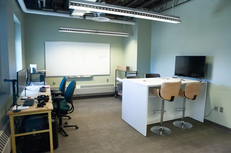 Classroom with desks, chairs, whiteboard and computers in Klai Hall 