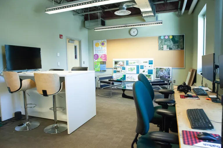 Classroom with desks, chairs, corkboard and computers in Klai Hall 