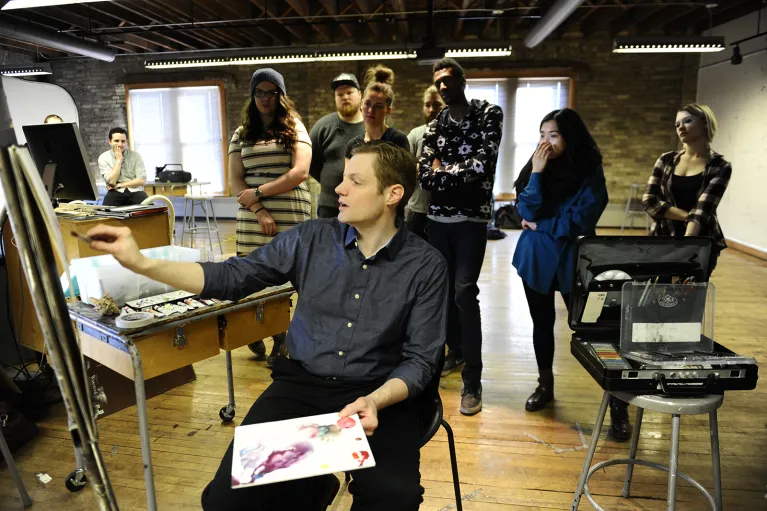 Faculty teaching while painting in painting studio.