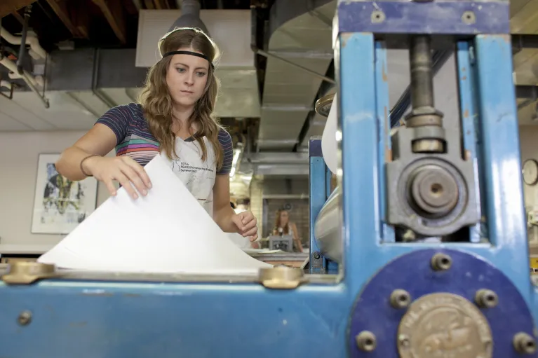 Student working with printmaking equipment in the printmaking studio.