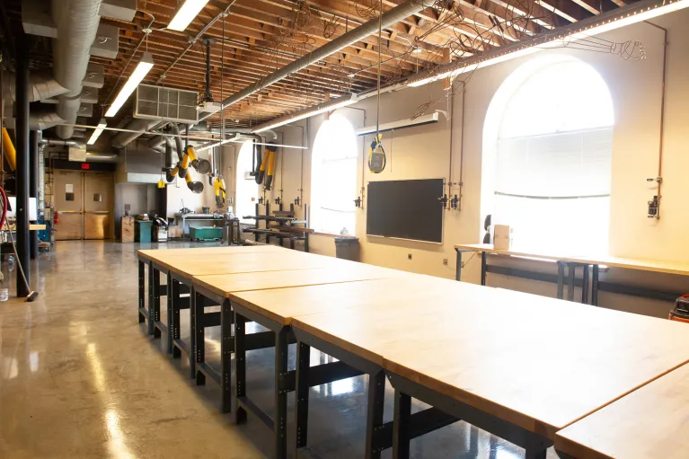 Sculpture studio with large table, windows and equipment.