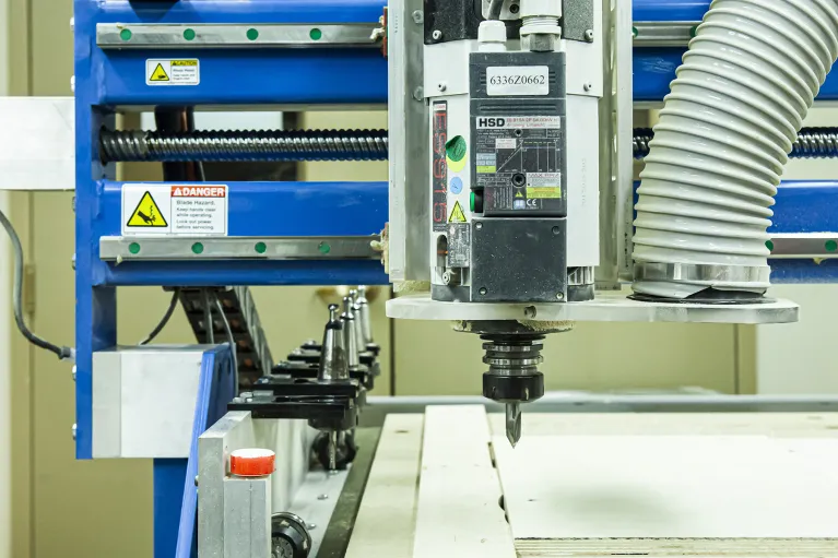 Machine cutting wood located in woodshop.