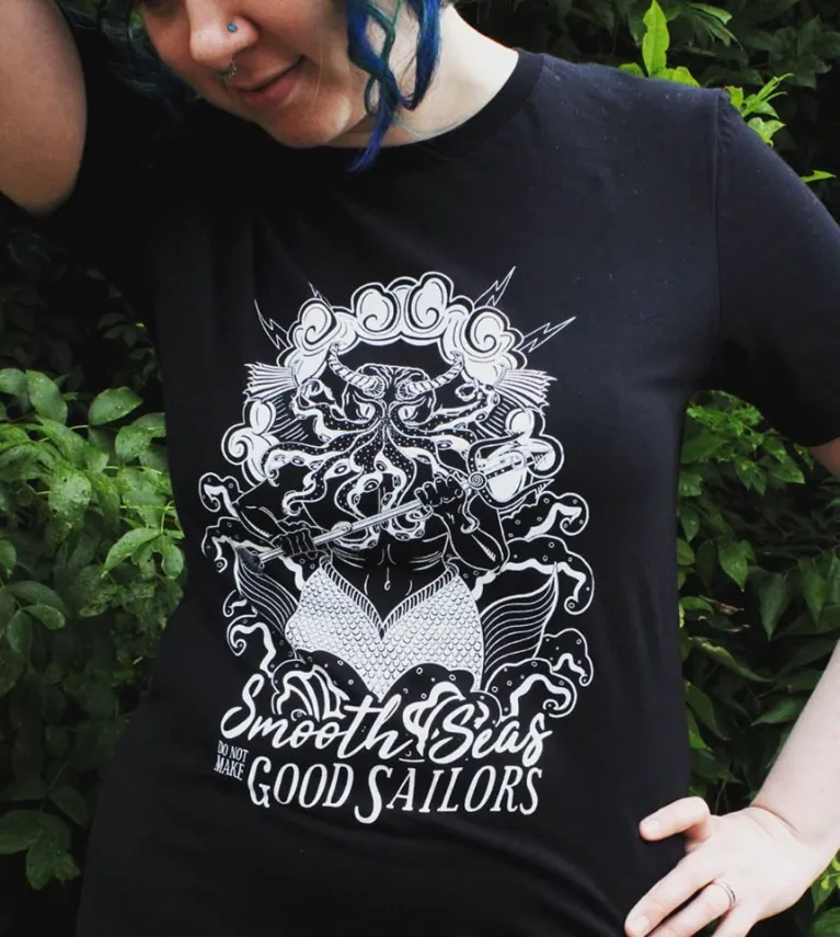 Model wearing black tshirt with artwork and 'Smooth Seas do not make Good Sailors' quote.