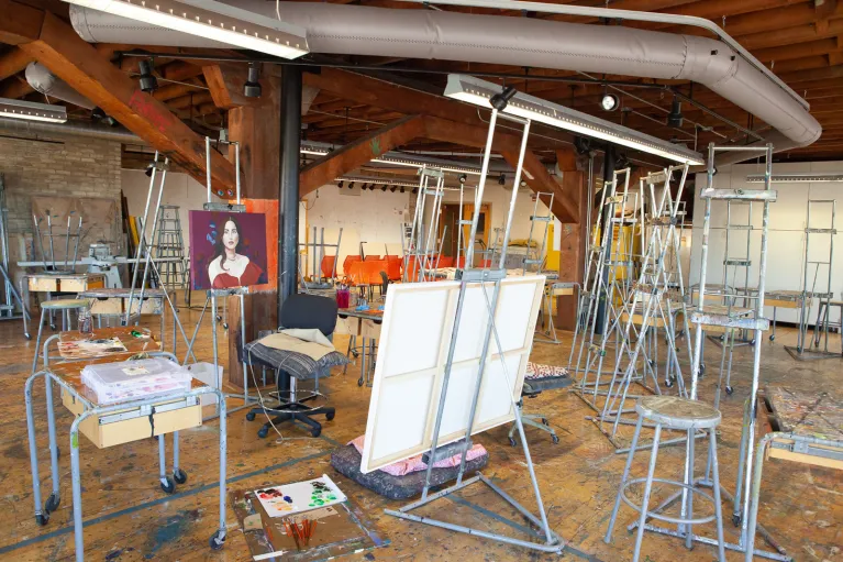 Easels, stools and artwork in painting studio.