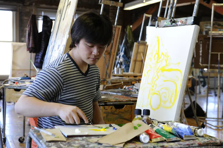 Student working with yellow paint on canvas.