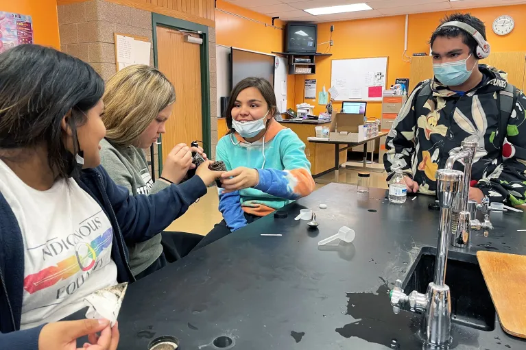 Teenage youth examine a filled jar.