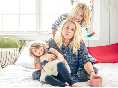 Two young children climb on their exhausted mother.