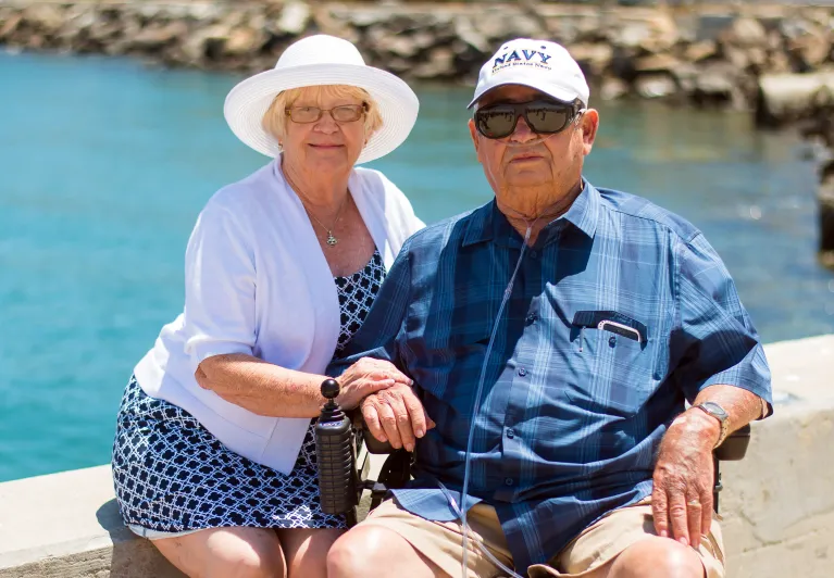 An elderly couple sitting near the water