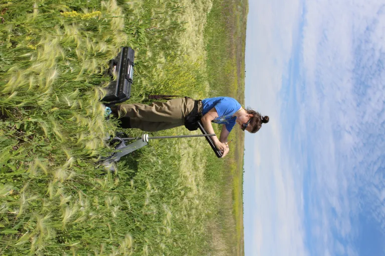 Standing in prairie collecting data on surrounding upland